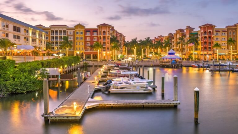 a marina at dusk with boats docked in front of buildings