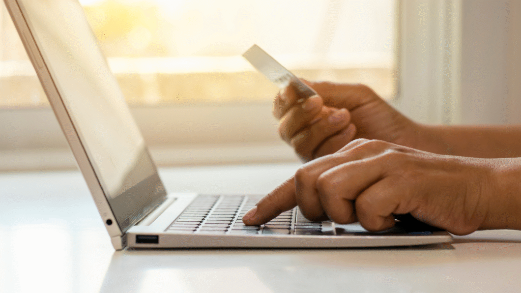 A person holding a credit card and using a laptop