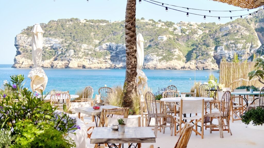 an outdoor dining area with chairs and umbrellas overlooking the ocean
