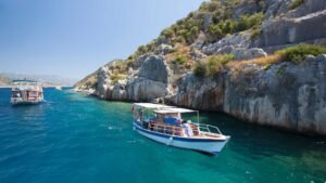 two boats in the clear blue water near a cliff