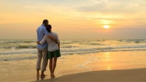 Two people standing on the beach at sunset